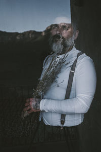 Mature man holding flowers standing indoors