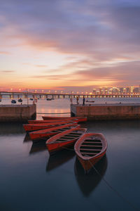 Boats moored in sea against sky during sunset