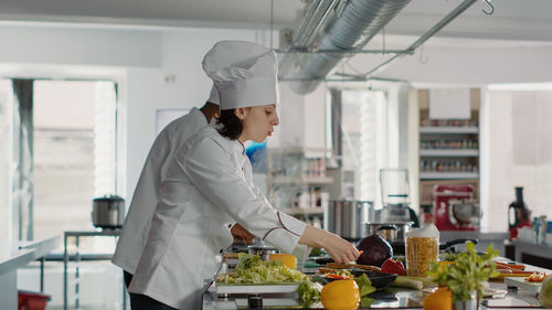 Side view of chefs working at kitchen