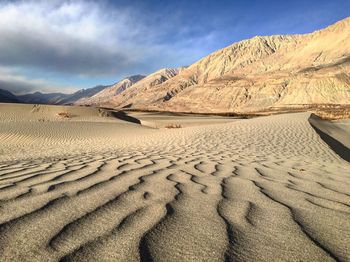 Sand dunes in desert against sky