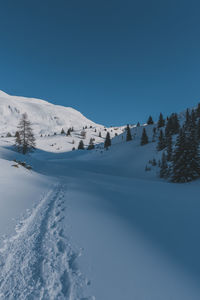 A picturesque landscape view of the snowcapped french alps mountains with a hiking path in the snow