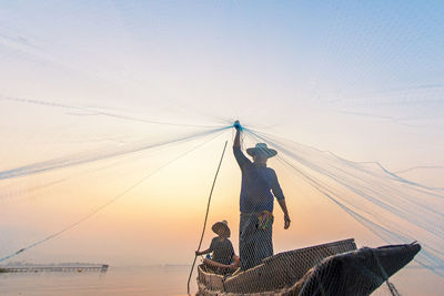 Fishing net on shore against sky during sunset