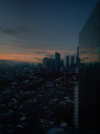 Modern buildings in city against sky at sunset