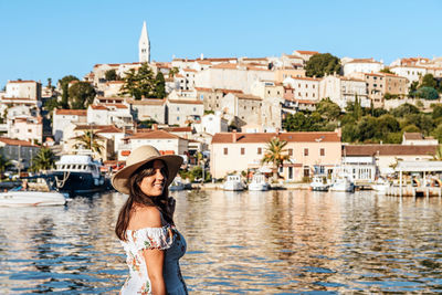 Portrait of smiling woman against buildings in city, old town by sea, summer, travel.