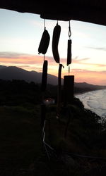 Cross on clothesline against sky during sunset