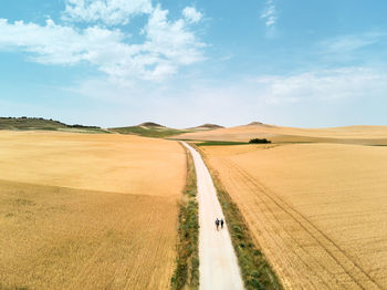 Panoramic view of road amidst field against sky