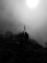 Silhouette people standing on land against sky