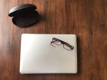 Close-up high angle view of laptop and eyeglasses on wooden table