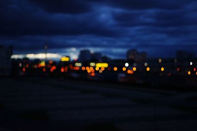 Illuminated road against cloudy sky