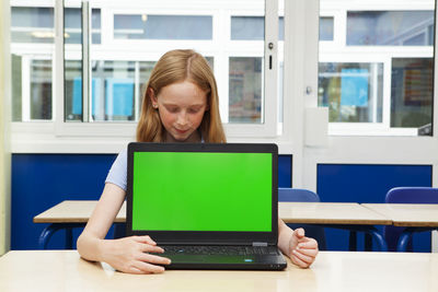 Woman using phone while sitting on table