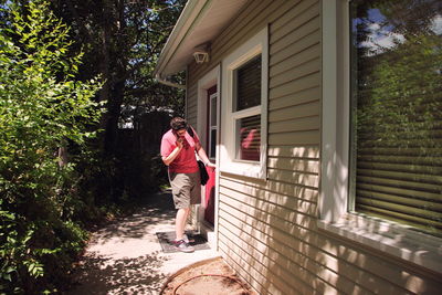 Woman talking on mobile phone while standing by doorway