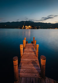 The island of san giulio with a wooden pier in the foreground at sunset, blue hour,  long exposure