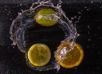 Close-up of lemon slice in water against black background