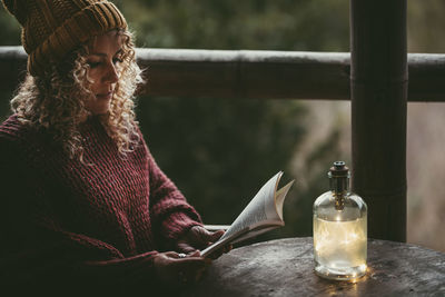 Side view of young woman sitting by railing