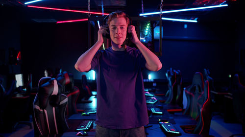 Portrait of young man standing in internet cafe