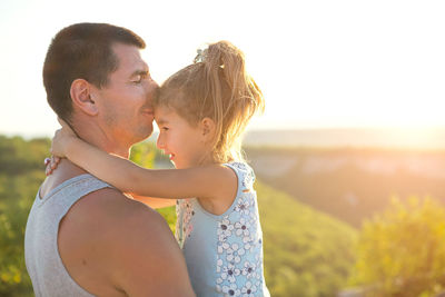 The father and daughter hug tightly, the girl holds the father by the neck, the father 