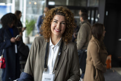 Smiling businesswoman with curly brown hair at conference center during seminar