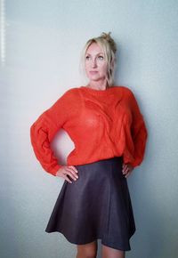 Beautiful woman looking away while standing against wall