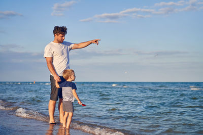 Full length of men standing at beach against sky