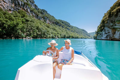 People on boat in sea against sky