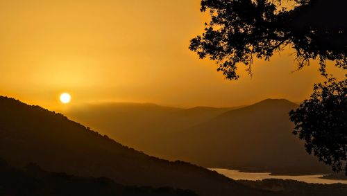 Scenic view of silhouette mountains against orange sky, sunrise