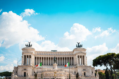 Italian flags by altare della patria against cloudy sky