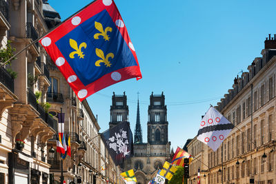 Low angle view of flags hanging against buildings in city