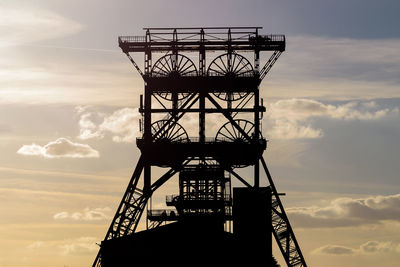 Low angle view of electricity pylon against sky during sunset