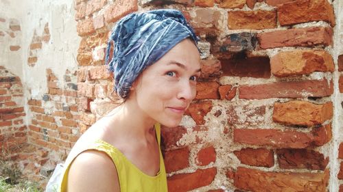 Portrait of woman by brick wall