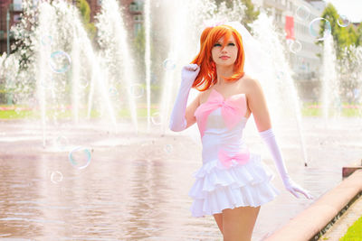 Woman with redhead wearing dress against fountain