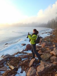 Woman using phone by lake