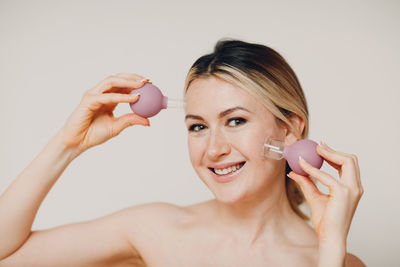 Portrait of smiling woman holding vacuum cup against colored background