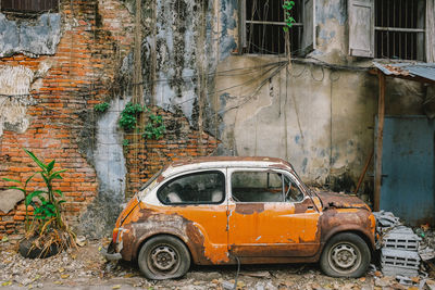 Abandoned car against brick wall
