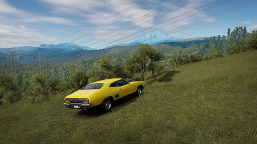 Yellow car on land against sky