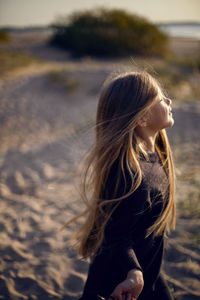 Portrait of a girl with long hair run on a sandy beach in a black leather jacket