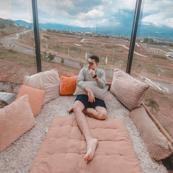 High angle view of young man sitting on window