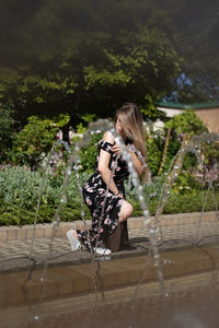 Young woman standing by fountain at park