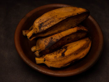 Stack of boiled bananas on a round pottery plate. shoot on a black background