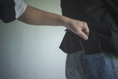 Cropped hand burglar removing mobile phone from man pocket