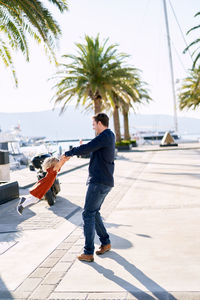 Side view of man walking on palm trees