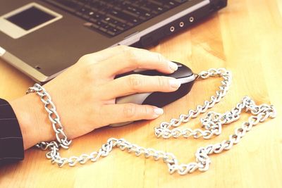 Cropped hand with chain using laptop at table