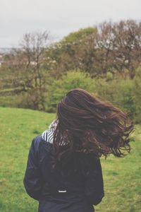 Rear view of woman tossing hair against trees