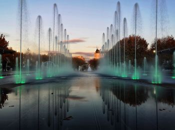 Panoramic view of lake by buildings against sky at sunset