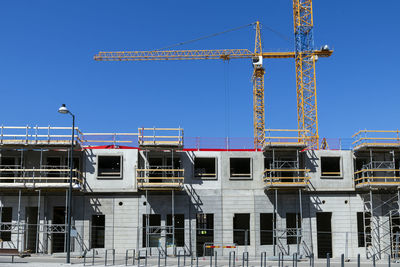 View of construction site with building crane against blue sky