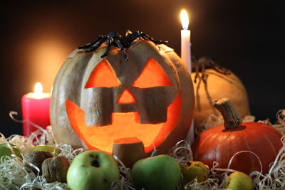 Close-up of pumpkins against illuminated candles