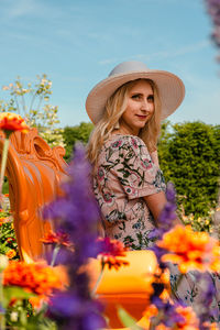 Beautiful young woman sitting against plants