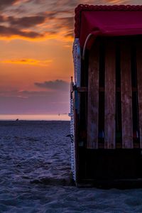 Hooded chair at beach during sunset