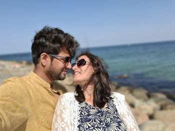 Couple kissing at beach against sky