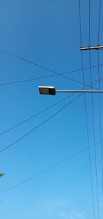 Low angle view of power lines against clear blue sky