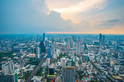 Aerial view of city buildings against sky during sunset